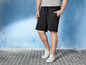 Man in zwarte shorts en witte sneakers.