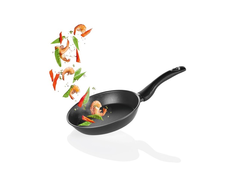 Een zwarte pan met garnalen, paprika en sperziebonen