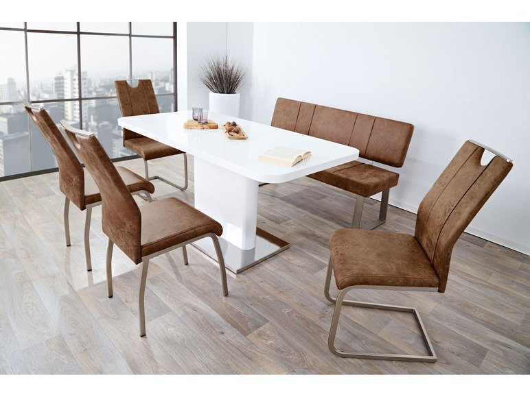 Een witte eettafel met vier bruine stoelen en een bankje.