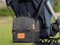 Een zwarte babytas van  Boodschappentas, bevestigd aan een kinderwagen.