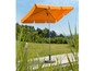 Een oranje parasol met een voet op een houten vlonder.