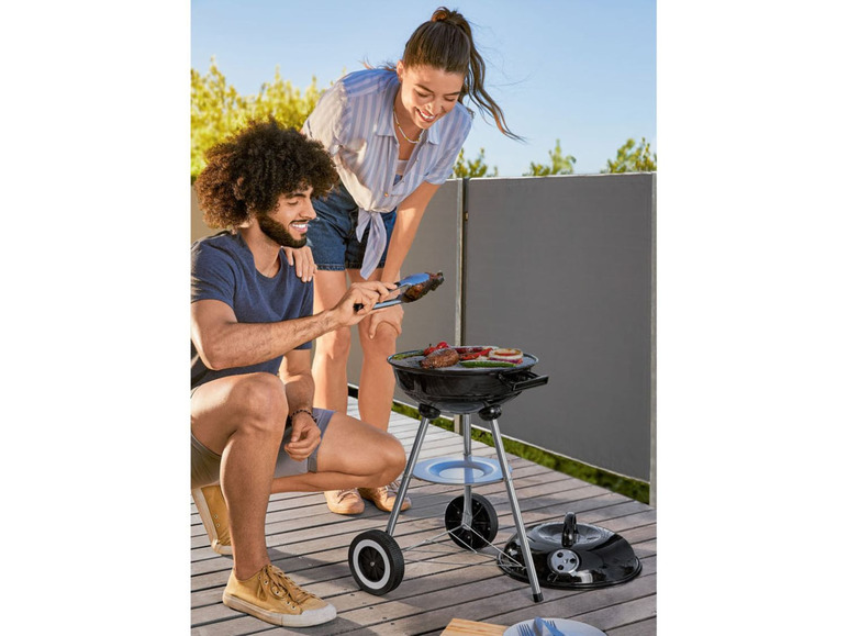 Een stel barbecuet op een terras met een draagbare barbecue.