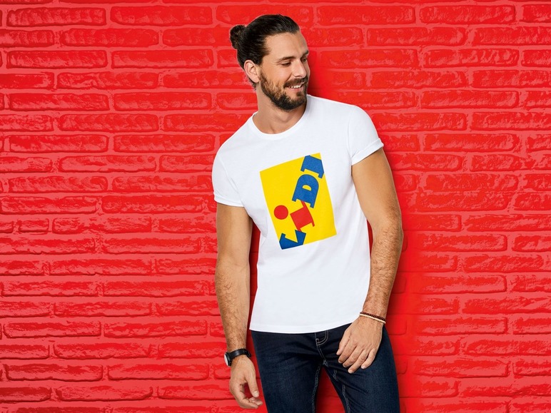 Man met een wit T-shirt met het Lidl-logo tegen een rode bakstenen muur.