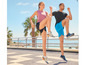 Twee personen doen oefeningen in sportschoenen op een strandpromenade.