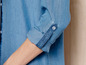 Een blauwe denim blouse met een opgerolde mouw.
