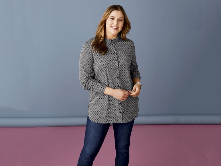 Een vrouw draagt ​​een gebloemde blouse en een spijkerbroek.