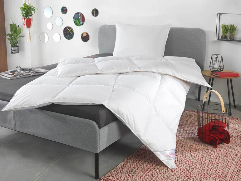 Een wit donsdekbed van het merk Sanitized op een grijs bed.
