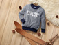 Een grijs sweater met de tekst 'EXPLORE' en twee houten ski's.