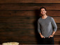 Man in een grijs T-shirt voor een houten achtergrond.