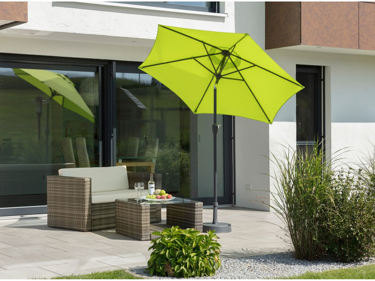 Een groene parasol op een terras met een loungeset.