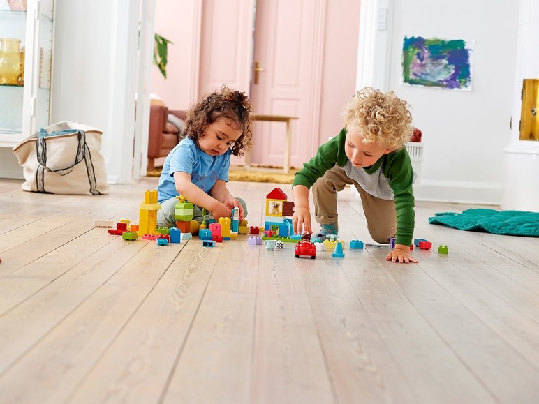 Twee kinderen spelen met LEGO DUPLO-blokken en auto's.