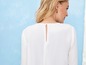 Een witte blouse met lange mouwen en een knoopsluiting op de rug.