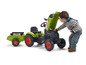Een kind speelt met een groene Claas tractor met aanhanger.