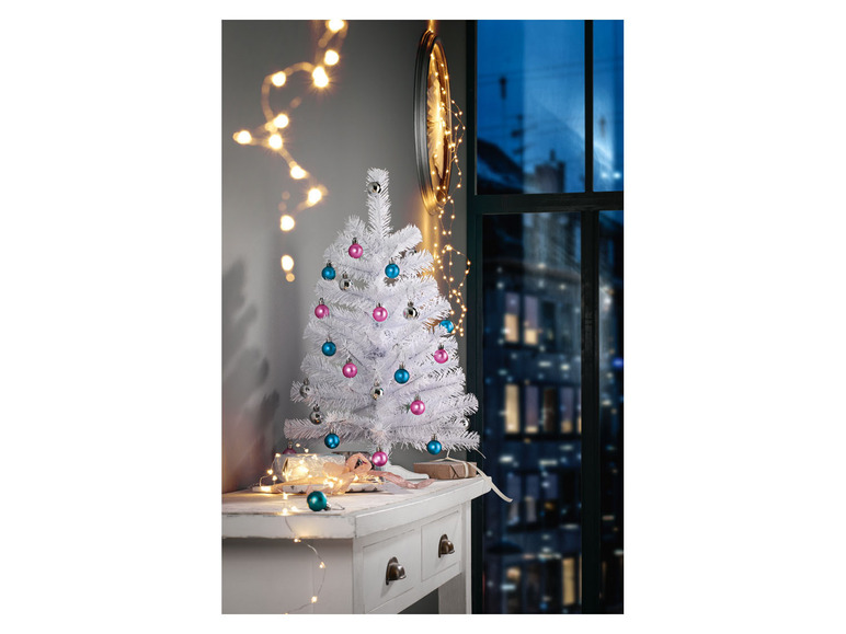 Een witte kerstboom met roze en blauwe kerstballen en lichtslingers.