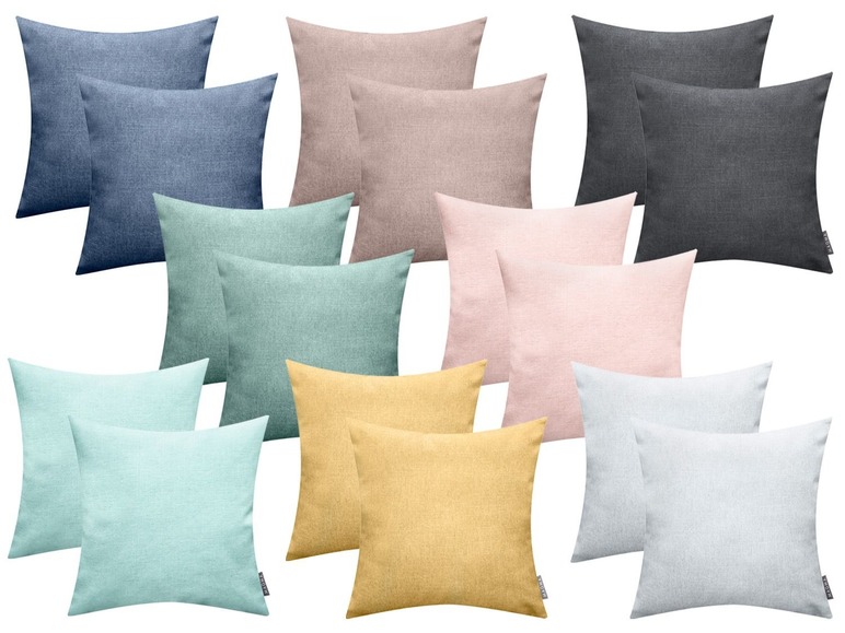 Kussens in diverse kleuren, waaronder grijs, roze en lichtblauw.