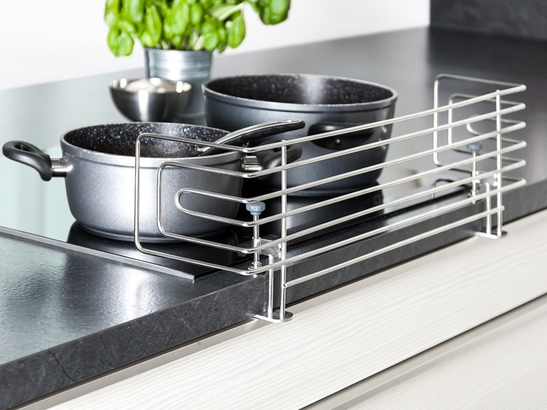 Twee pannen op een kookplaat met een metalen veiligheidsscherm.