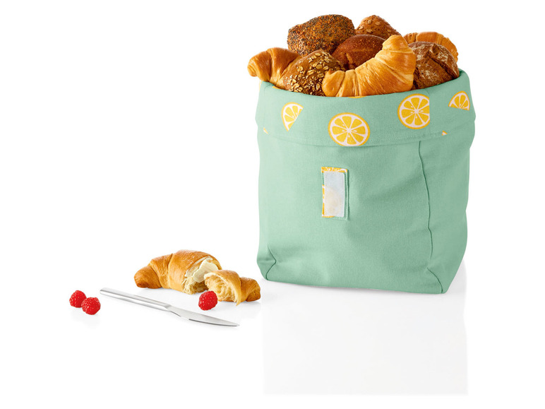 Een groene broodmand met citroenenprint, gevuld met croissants en broodjes.