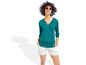 Een vrouw draagt een turquoise blouse met witte shorts.