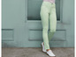 Een vrouw draagt ​​lichtgroene jeans en witte schoenen.