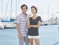 Een man en vrouw in gestreepte zomerkleding op de achtergrond van een jachthaven.