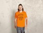 Man draagt een oranje T-shirt met een industriële print.