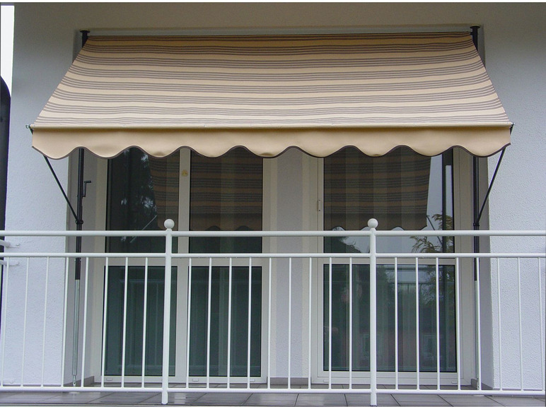 Een gestreept zonnescherm boven een balkon met een witte railing.