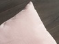 Een roze kussen op een houten vloer.