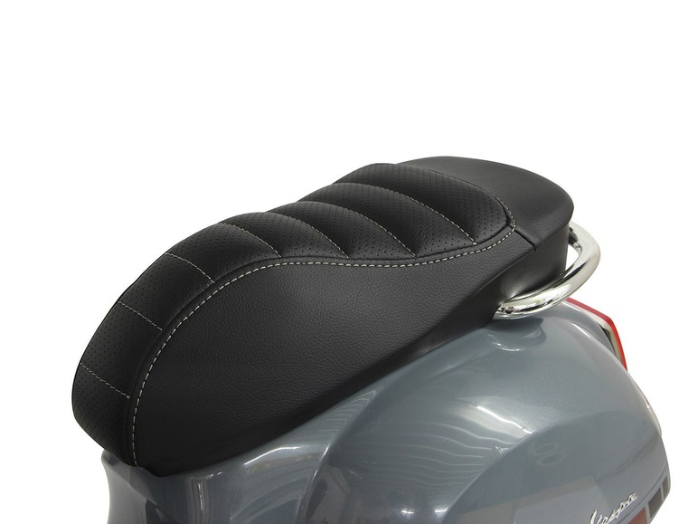 Een zwart leren zadel met stiksels voor een Vespa scooter.
