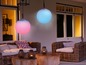 Twee hangende kleurveranderende lampen, roze en blauw, boven een lounge set.