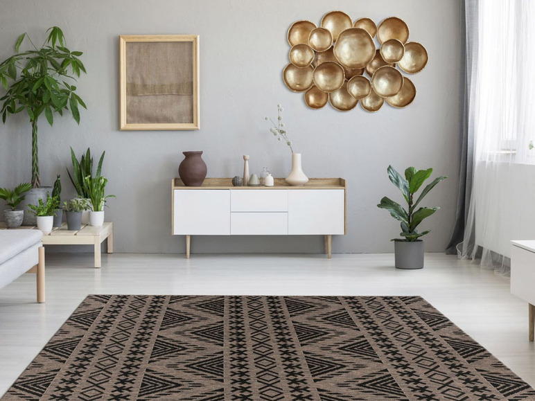 Een modern interieur met een geometrisch tapijt en een wanddecoratie van gouden schijven.