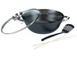 Een zwarte wok met glazen deksel, spatbescherming, spatel en eetstokjes.