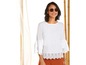 Een vrouw in een witte blouse met borduursels en een oranje broek, draagt een zonnebril