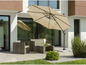 Een beige parasol met een wicker loungeset op een terras.
