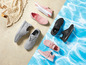Grijs, roze en zwarte sneakers op een strandachtergrond.