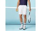 Man met witte tennisshorts, een tennisracket en een bal bij een tennisnet.