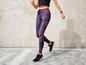 Vrouw draagt sportleggings met print en zwarte sneakers.