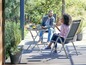 Twee personen zitten op vouwstoelen aan een ronde tuintafel.