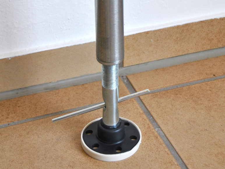 Een metalen paal met een schroefdraad en een zwarte voet op een tegelvloer.