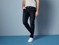 Man draagt donkerblauwe jeans en witte sneakers.