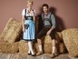 Een man en vrouw in traditionele Duitse kleding, met strobalen op de achtergrond.