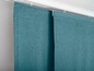 Twee turquoise gordijnen met een rail aan de bovenkant.