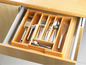 Een bamboe besteklade met bestek, messen en een garde.