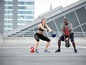 Twee mensen trainen met kettlebells op een dakterras.