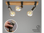 Drie verstelbare lampen met een houten rail en vintage gloeilampen.