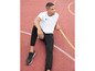 Man in Nike T-shirt en trainingsbroek op een atletiekbaan.