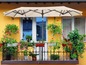 Een beige parasol boven een balkon met bloempotten.