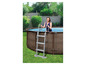 Een vrouw in een zwembad met een ladder en een zwembad.