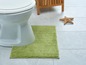 Een toilet met een groene badmat en een stervormige decoratie.