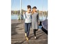 Twee vrouwen lopen in casual kleding op een houten pier aan het water.
