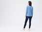 Een vrouw draagt een blauwe longsleeve en blauwe skinny jeans.